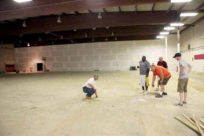 Construction workers measure out the future bowling lanes.