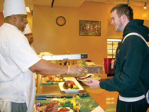 A food service worker from Fresh Ideas serves food to a student.