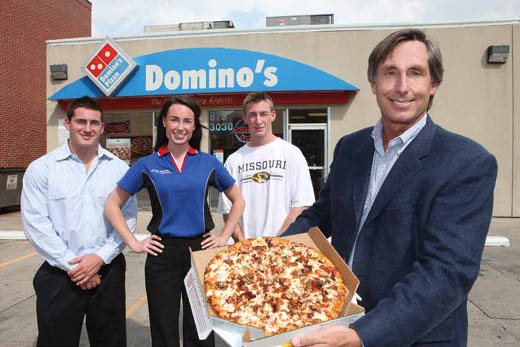 Greg Neichter shows off his favorite pizza in front of the Domino's Pizza on Ninth Street with his kids (from left) Peter, Eileen and Patrick. Neichter owns 35 Domino's Pizza outlets in Missouri and Kentucky.