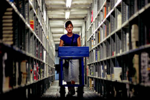 An employee sorts books in the three-story library at MBS Direct.