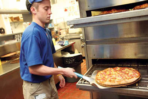J.P. Baker pulls a Hawaiian pizza out of the oven at Domino's Pizza.