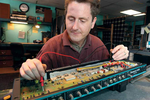 Dave VanSickle takes apart a guitar amplifier and checks the voltage.