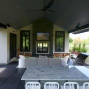 Covered outdoor living space with table chairs couch and TV