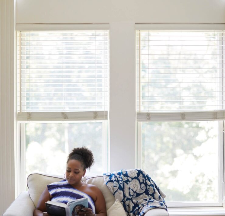 Adonica Coleman reading on her loveseat at home