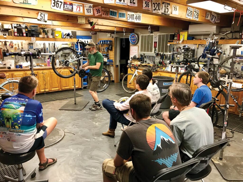 A man teaches cyclists how to repair a bike. 