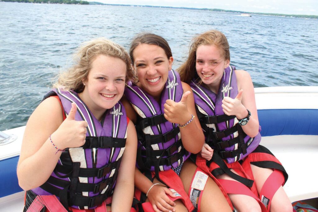 Three girls in a boat with life vests on