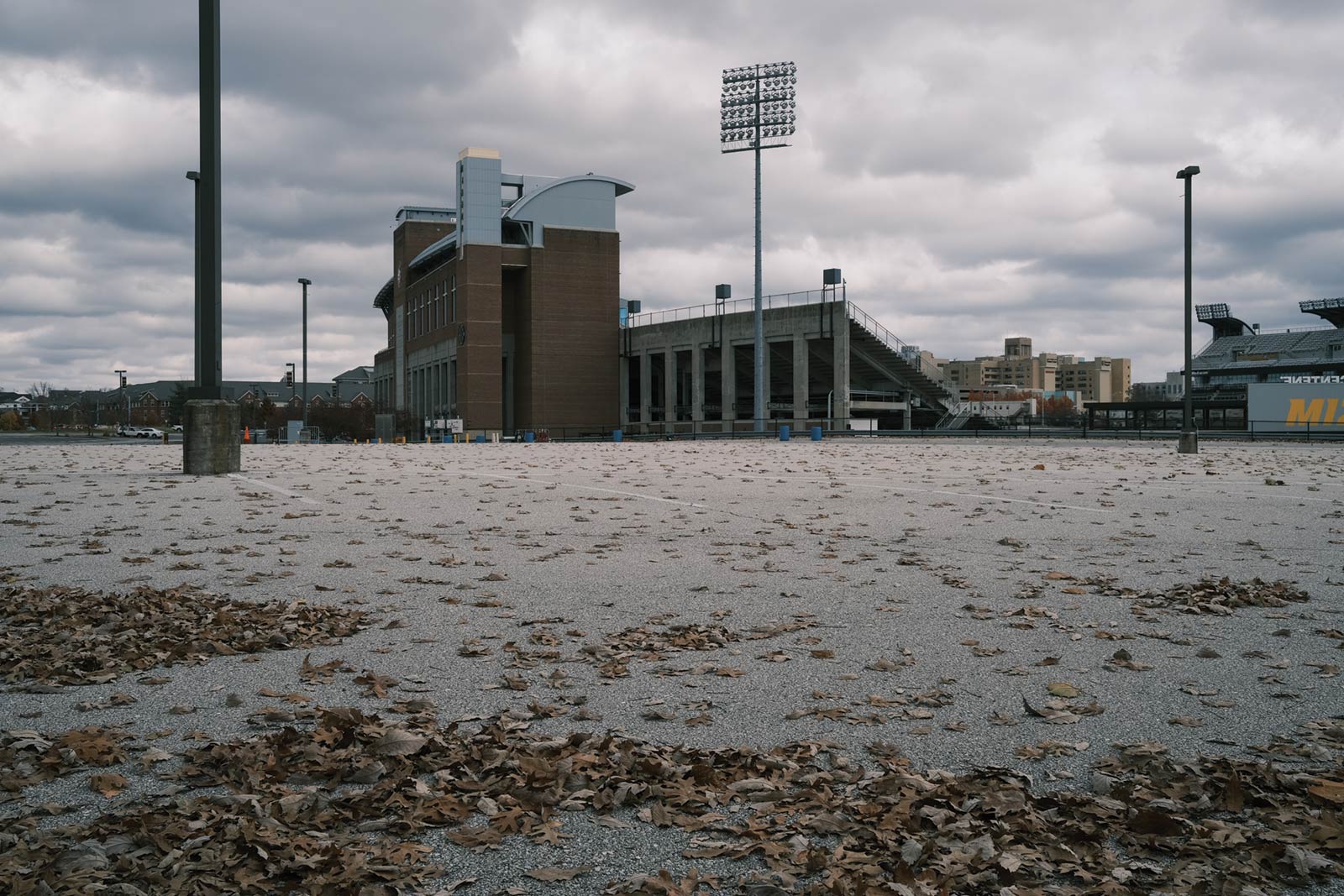 Empty parking lot covered in fallen leaves at Mizzou's stadium.