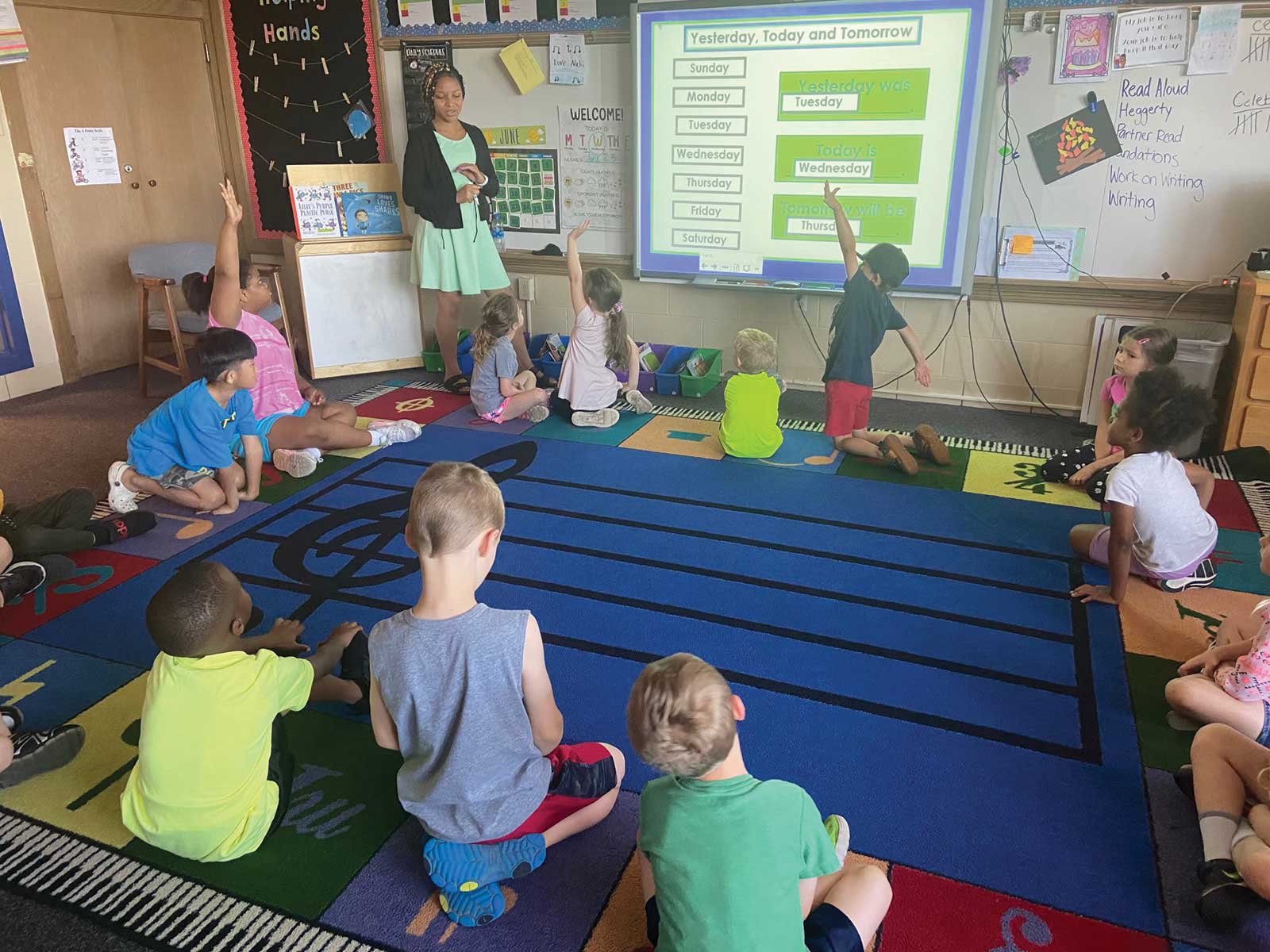 A teacher teaching a lesson to a group of small children inside of a classroom