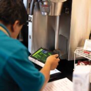 overlooking a barista's shoulder as he is using a tablet register