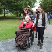 a family particiapting in a charity alzhemiers walk with one elderly women in a wheelchair