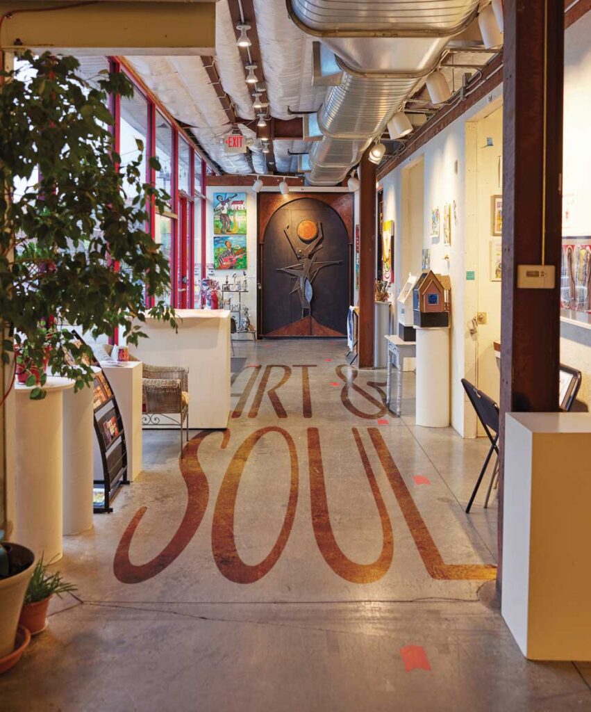 overview of the interior of a art studio with art hanging from each wall and the words 