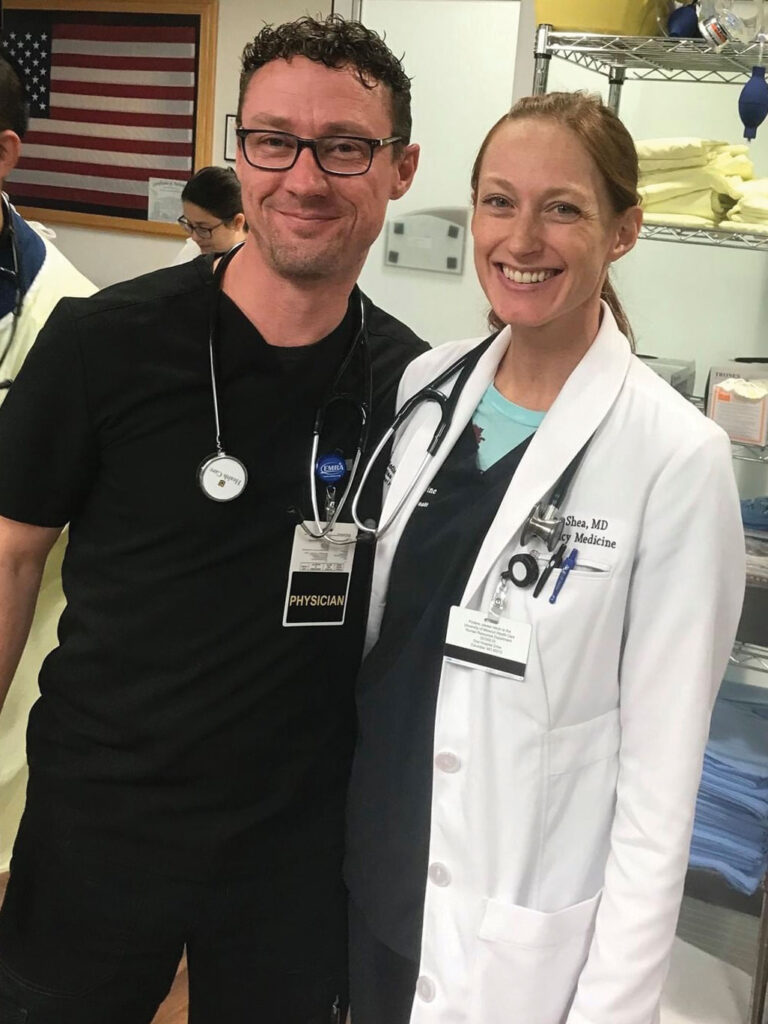 a man and women in scrubs pose in a medical office