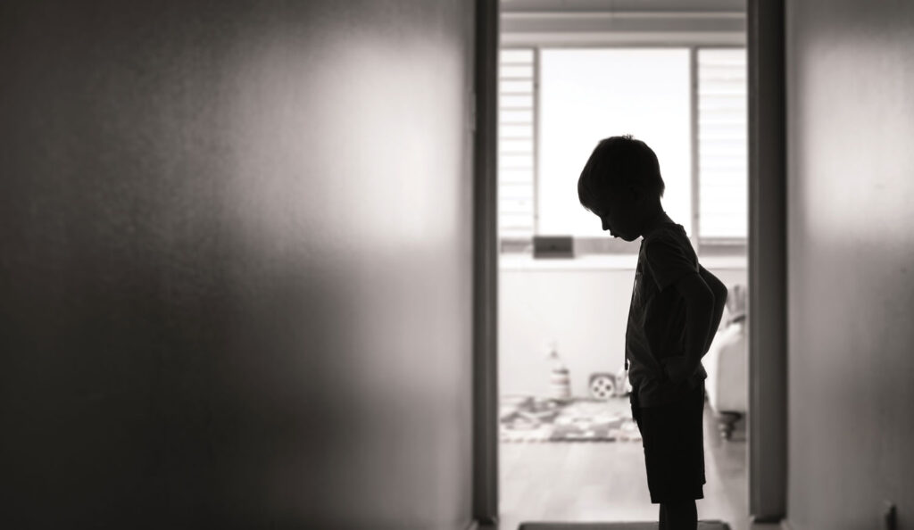 black and white photo of a young boy standing in a hallway