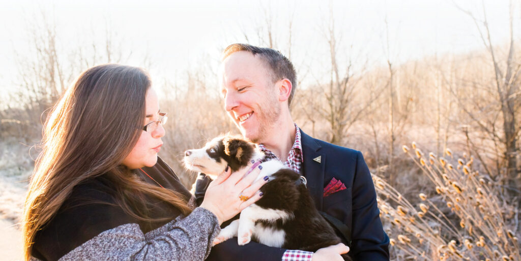 a man holding a puppy and a women stand in a field