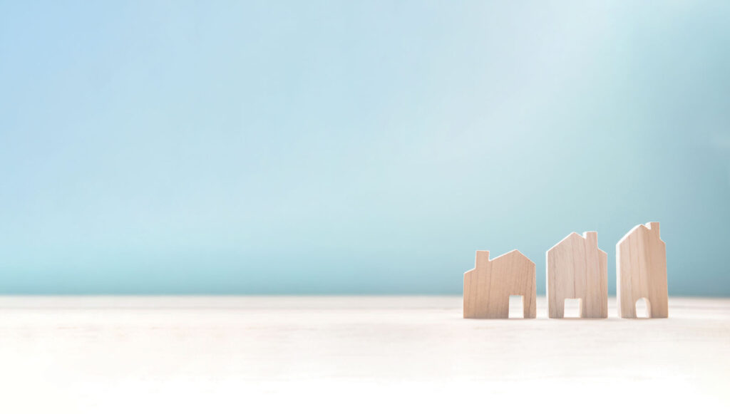 three small wooden houses on a white surface with a blue background