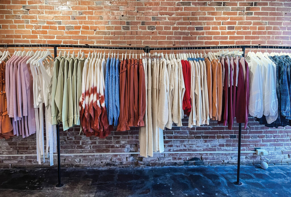 a rack of full clothes against a exposed brick wall