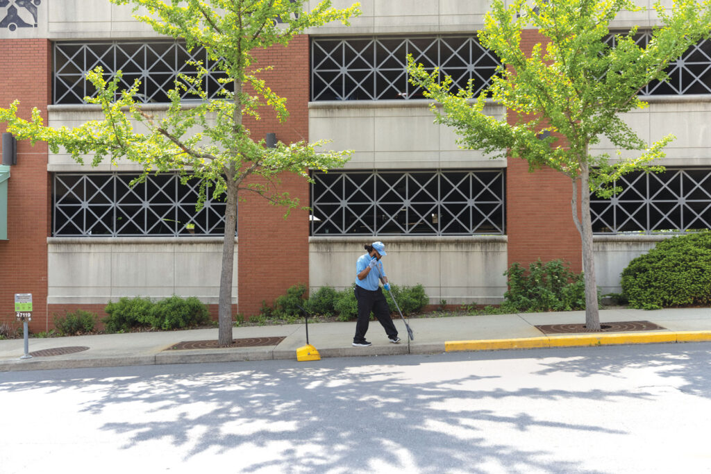 a downtown employee brushes a sidewalk downtown outside of a parking garage