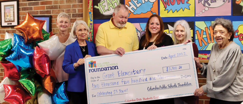 Teachers and board members of a local school accepting a large check of grant money