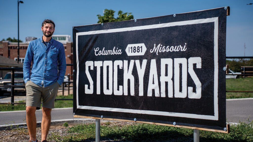 a young man stands out of a outdoor sign with the text 