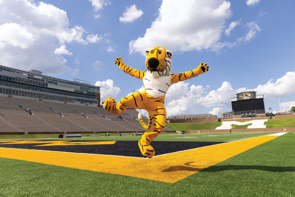 Truman the tiger in mid air jumping on Faurot football field