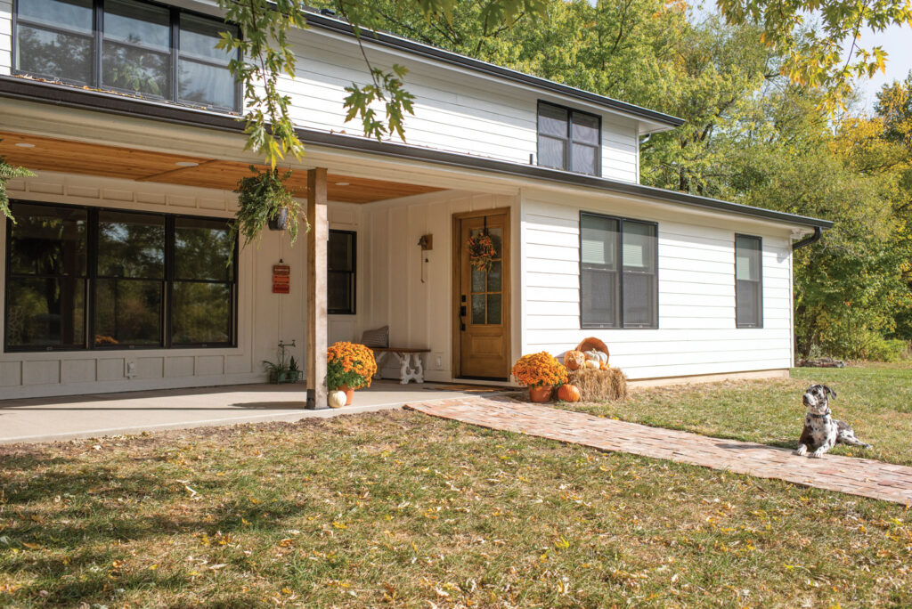 wide view of exterior of house with backdoor and dog resting in the yard