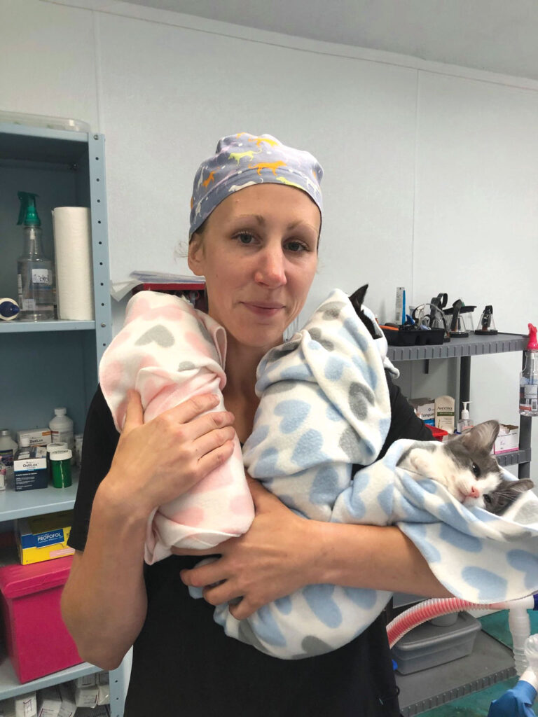 Registered Vet Tech named Carissa Luttrell cuddling three kittens bundled up after surgery