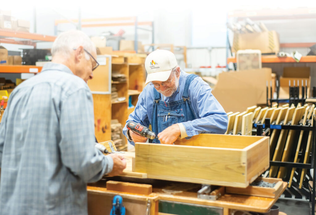 two Mobility worldwide volunteers assembling a cart