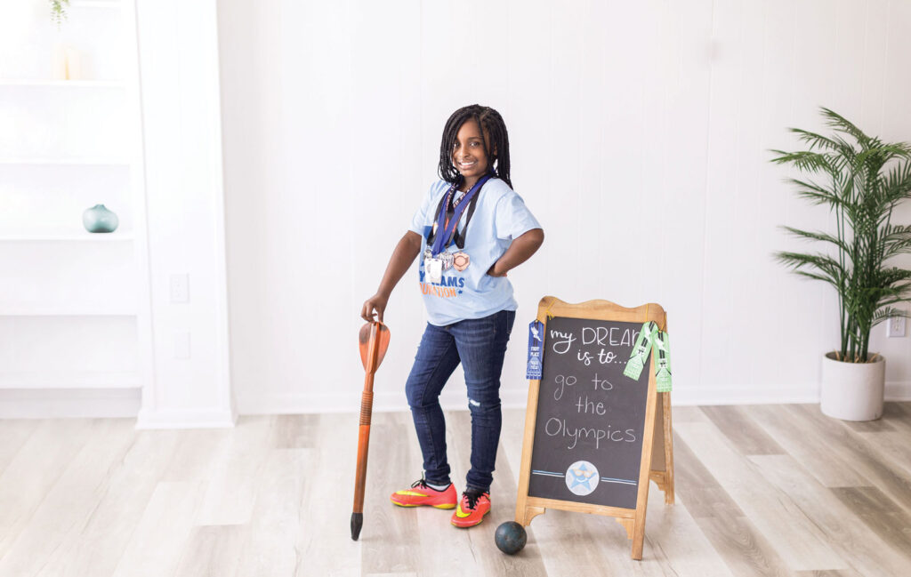 A young girl stands next to a chalkboard with says her dream is to 