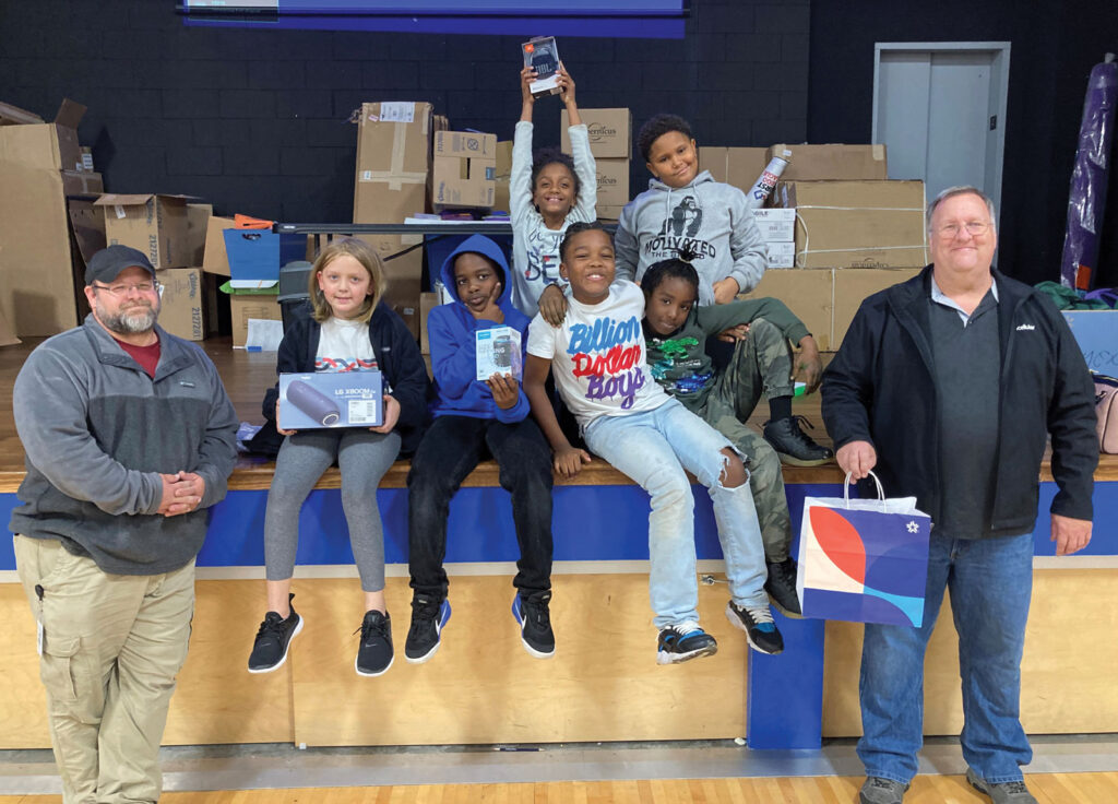 group of children apart of Boys & Girls Clubs of Columbia smile alongside UScellular’s Optimization Engineer Zach Perry and Senior Optimization Engineer Christopher Brinkman who organized a charity event