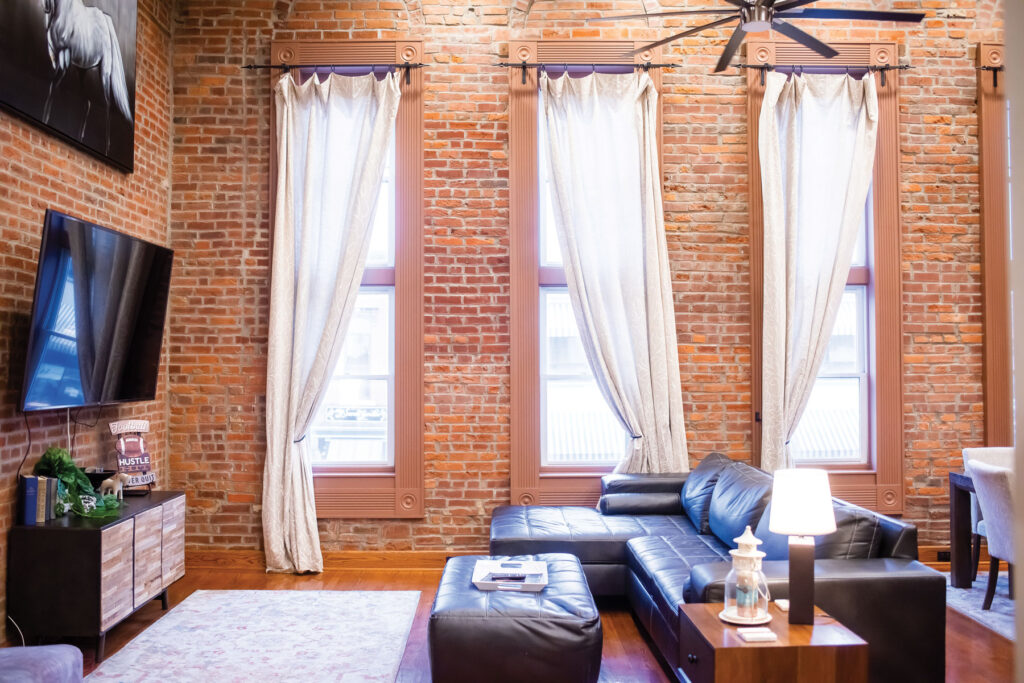 interior of a stylish living room with exposed brick walls and tall windows in an air bnb located in the heart of Columbia off broadway