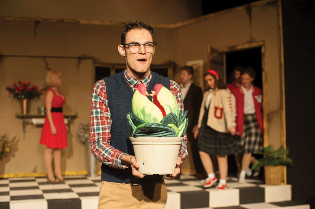 Actor in Little-Shop-of-Horrors play with several castmates in the background