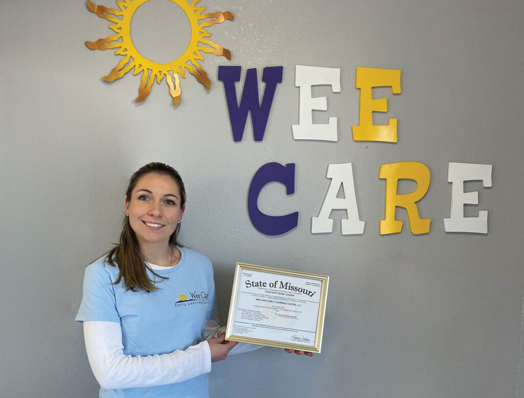 Wee Care employee holding State of Missouri Child Care Center license