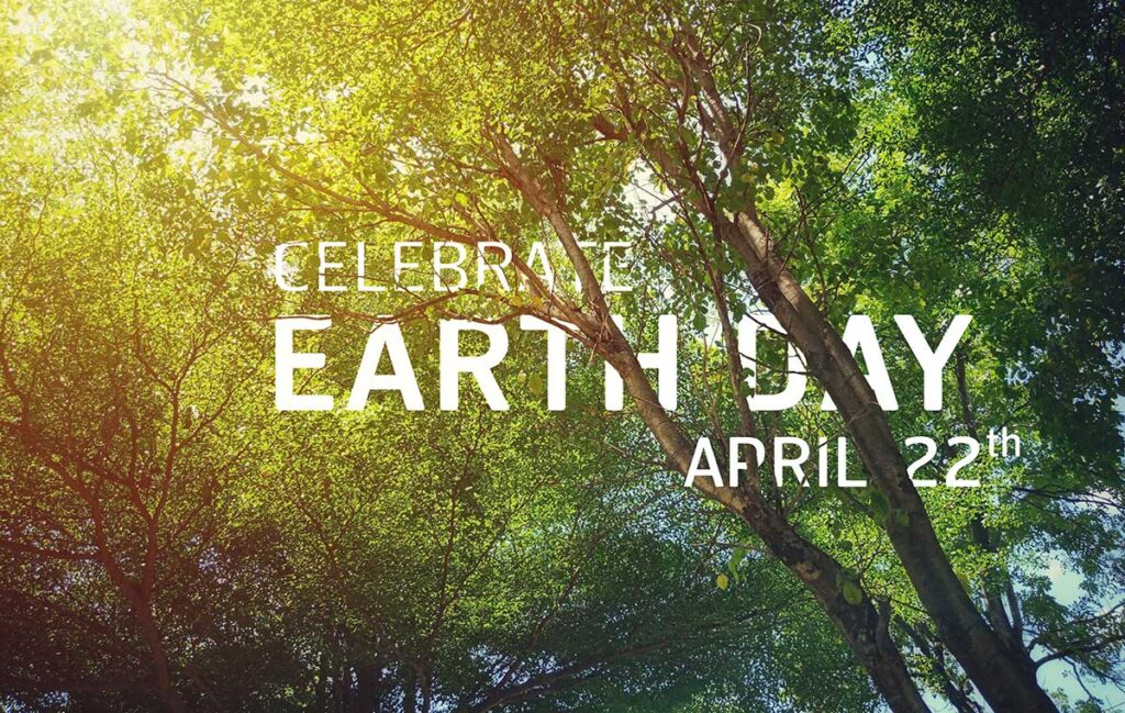 Celebrate Earth Day April 22 shows through the sunlight beaming through leaf-covered tree branches.