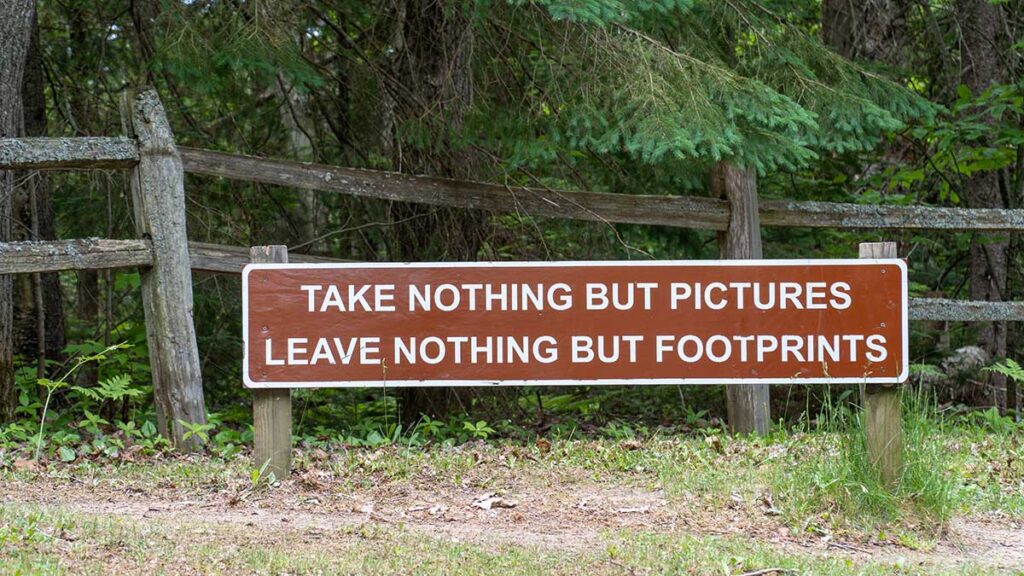 Brown and white sign saying Take Nothing But Pictures Leave Nothing But Footprints as instructions for hikers and campers. 