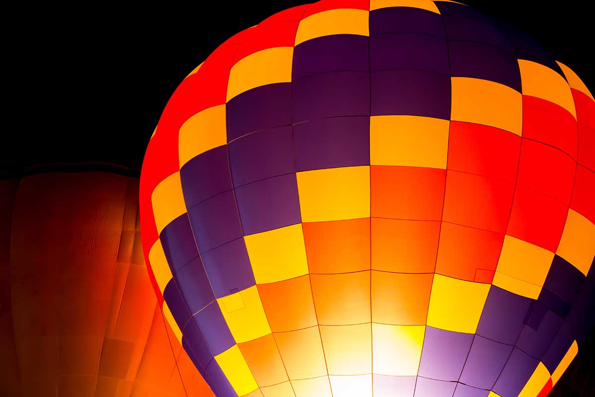 Image of a brightly colored hot air balloon against a dark night sky.