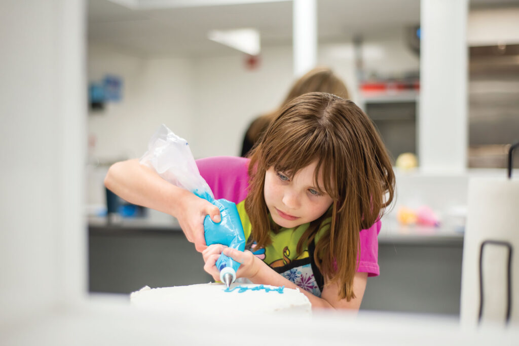 a young child Practicing cake Decorating Techniques