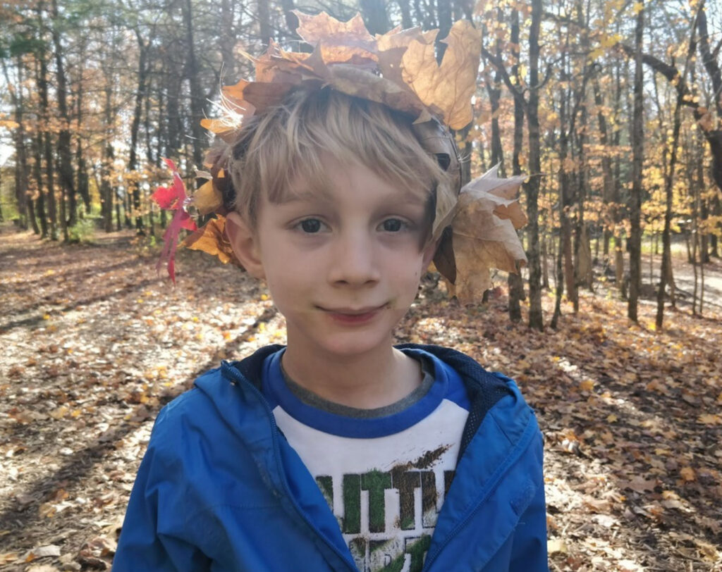 Young boy in a leaf crown outdoors during the fall