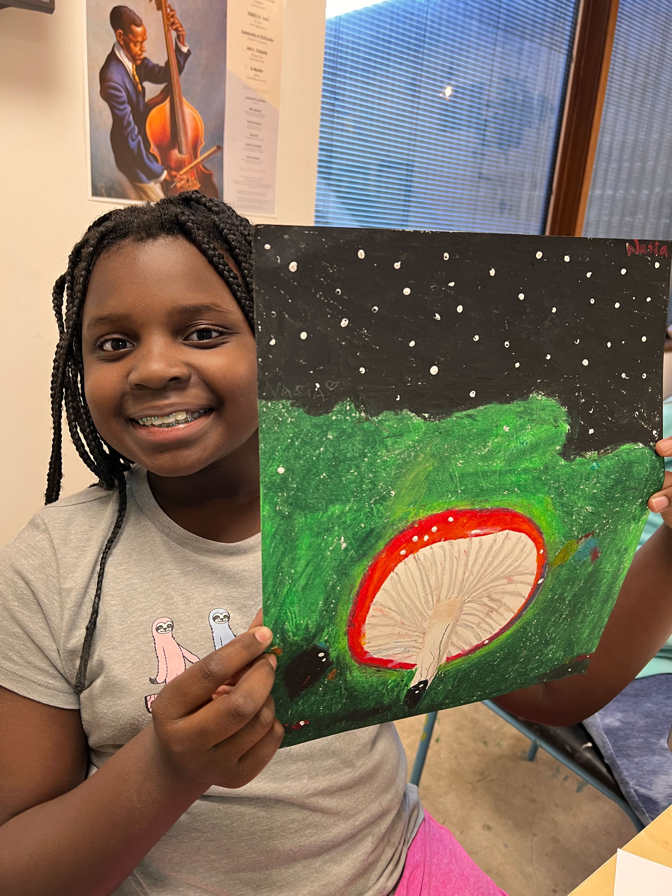 Nasia Chiteri displays her oil pastel drawing of a mushroom at night in illustration class.