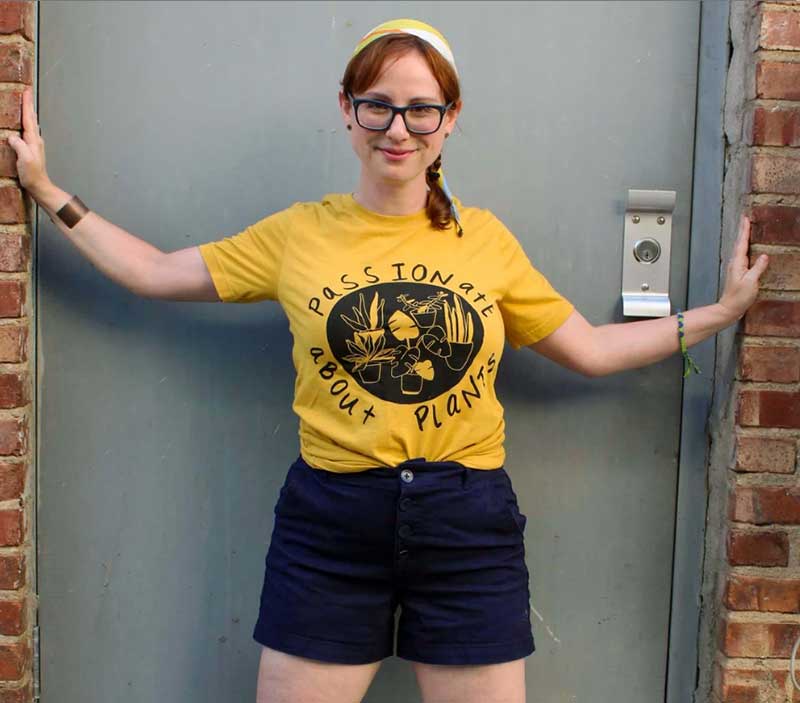 COMOMom Jennifer Book Haselswerdt models a yellow t-shirt with black lettering that reads, Passionate About Plants. 