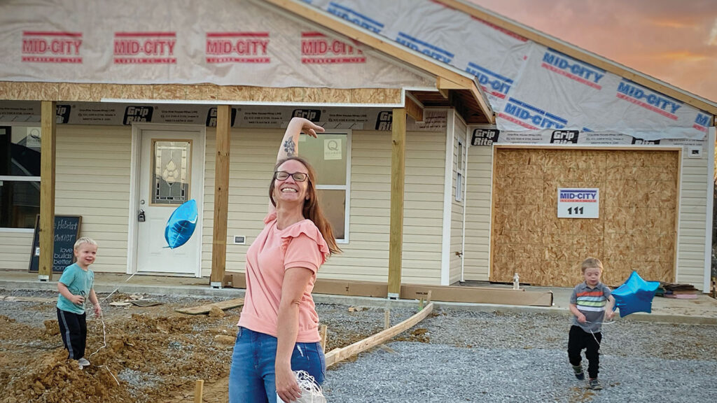 Angela at her family's new construction home with children playing in the yard