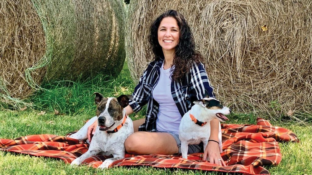 Angie Randazzo of Paws In Heaven with her two dogs outside on a blanket