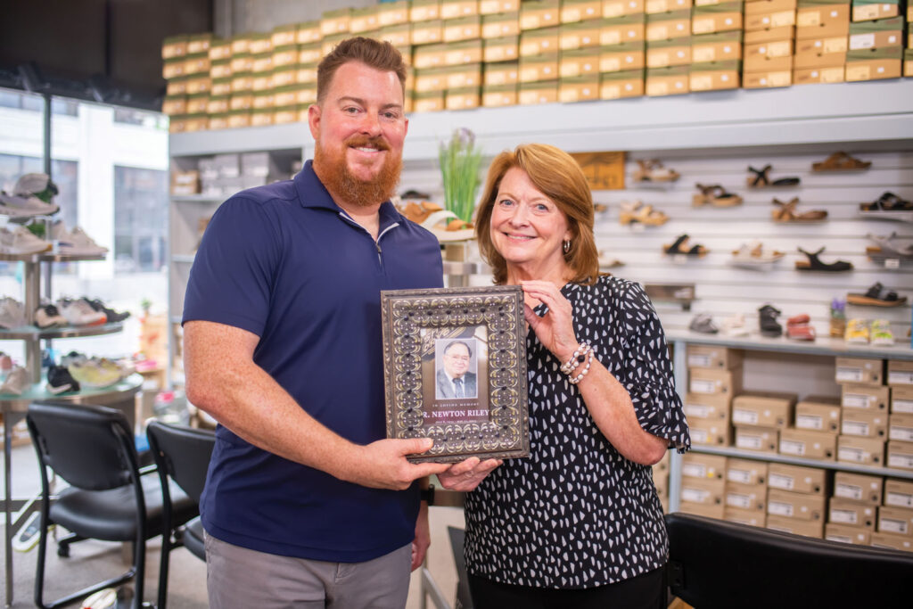 Justin Riley and Rebecca Rudd Holding photograph of R Newton Riley