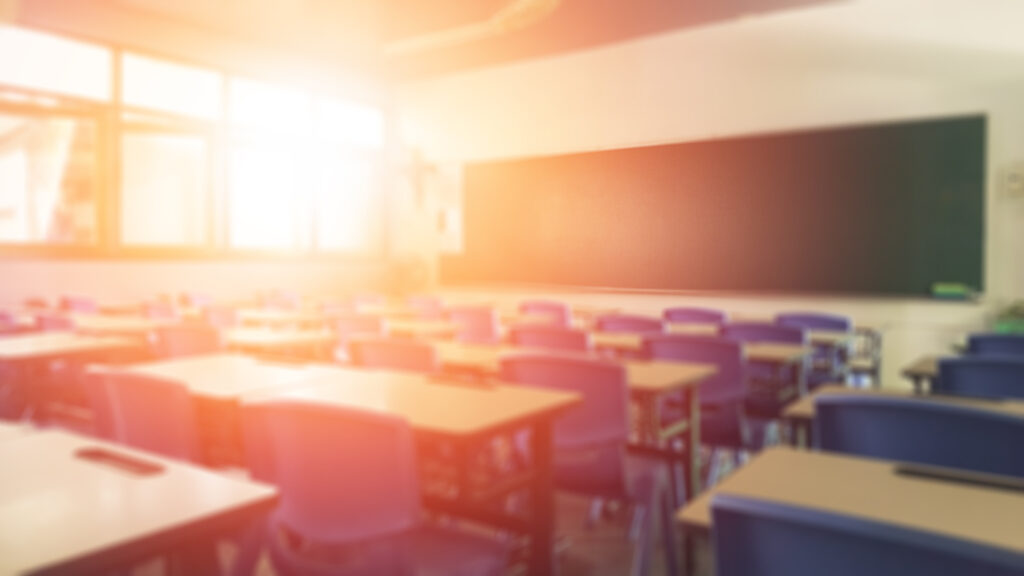 School Classroom In Blur Background Without Young Student; Blurry View Of empty Elementary Class Room With Chairs And Tables In Campus.