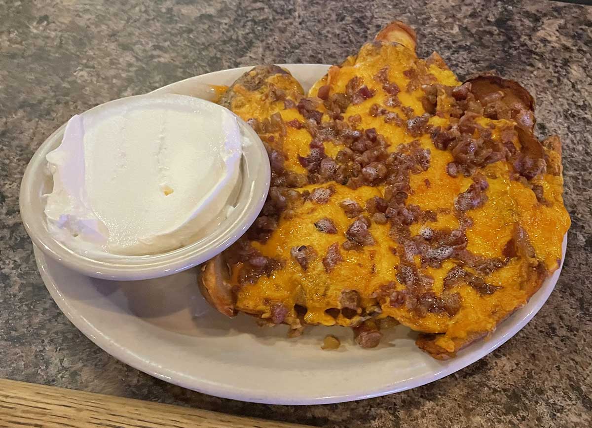 A plate of bacon and cheddar potato skins with dipping source, served up by The Heidelberg in Columbia, MO.