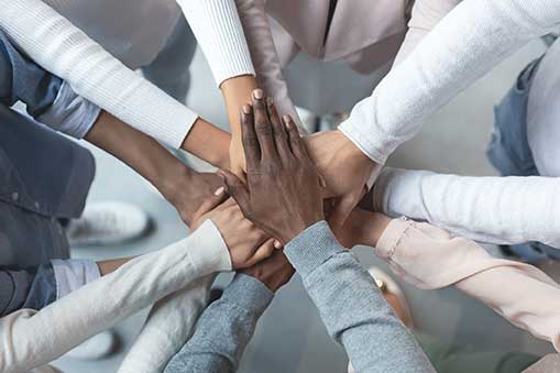 Gettyimages 1201450045 a bunch of people standing in a circle overlapping their hands