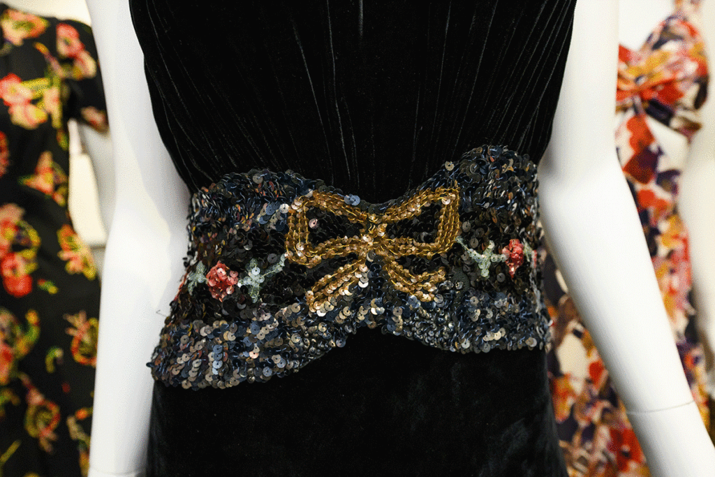 A star is born exhibit showcasing a vintage black dress with beaded belt in the shape of a bow