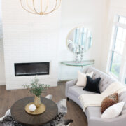 Wide shot of living room with tall white brick fireplace