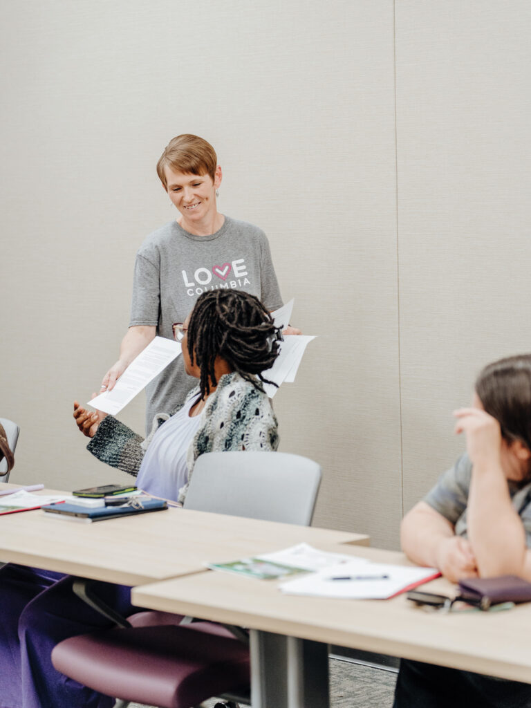 Instructor Hands Out Paper To Participant At Love Columbia Financial Class