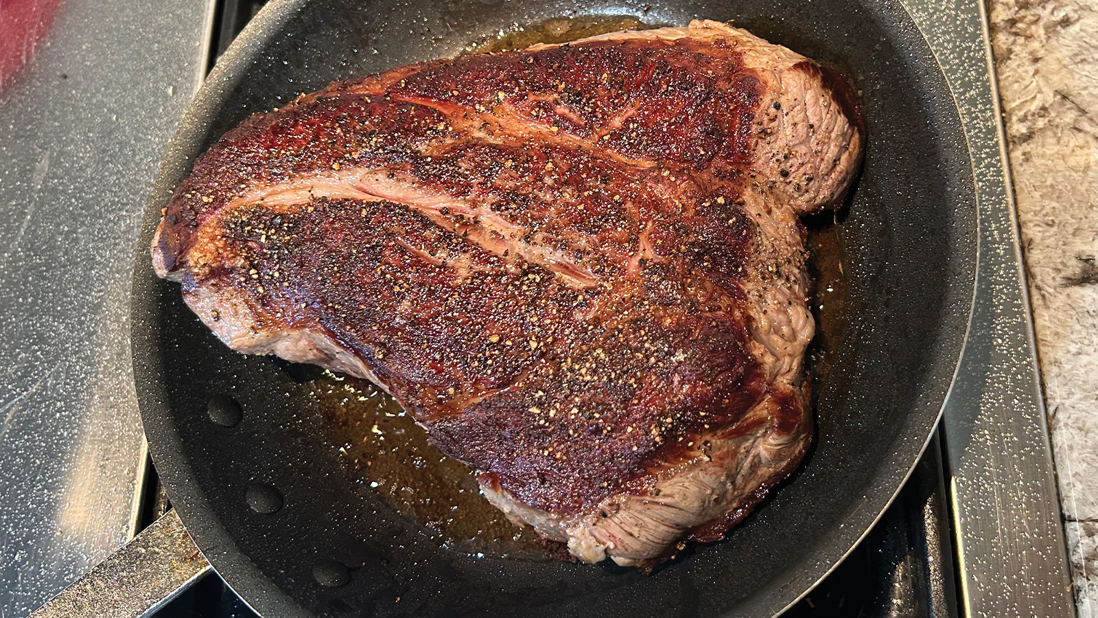 Searing a slab of steak on stovetop