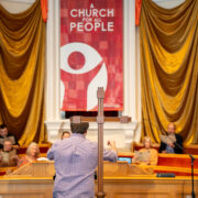 Wooden Cross On A Table With Candles And A Church Choir In The Background